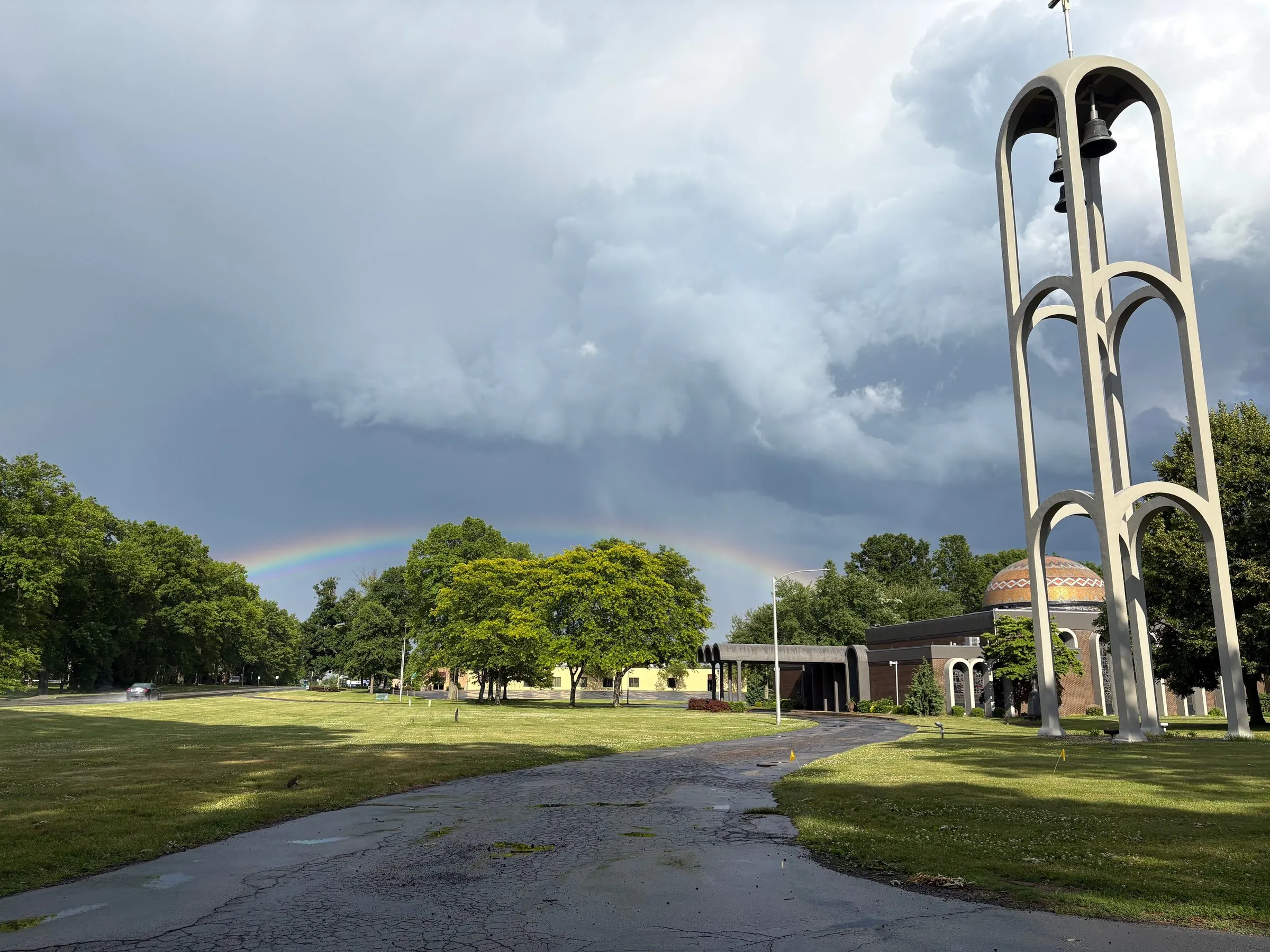 A rainbow arching over the bell tower and gold dome of a Byzantine church after a storm
